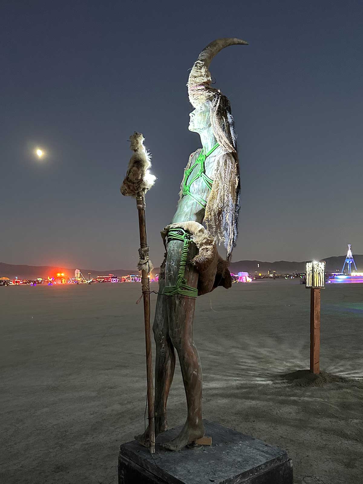 Shamanic figure sculpture with crescent horn under moonlight