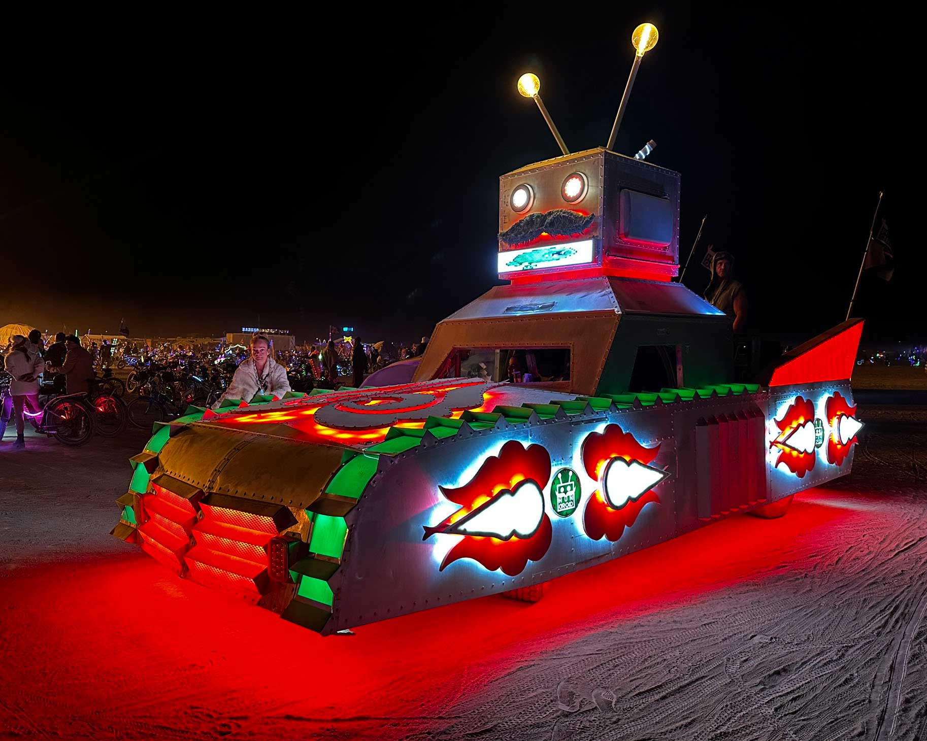 Illuminated robot art car with glowing lip graphics at night