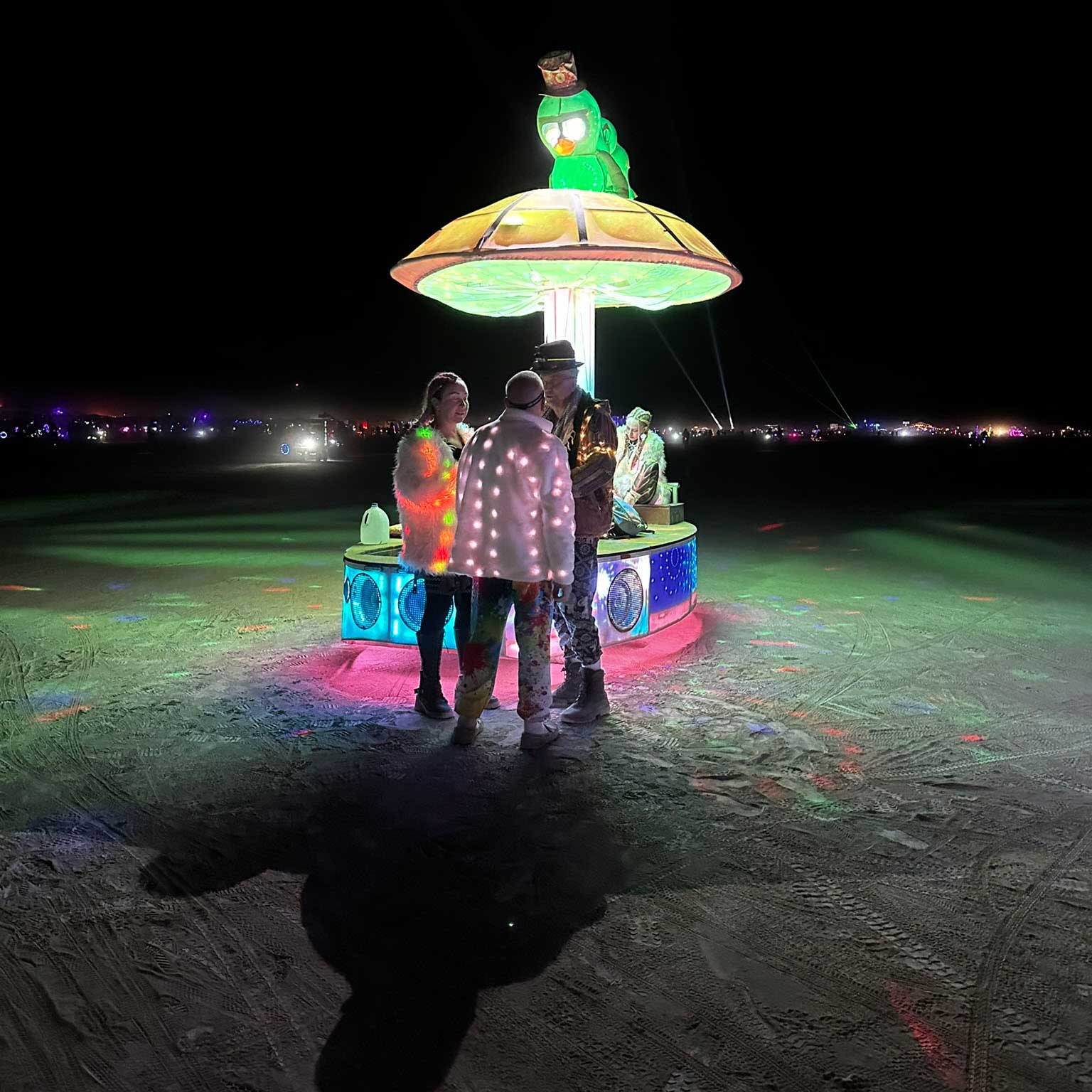 Costumed participants around a glowing mushroom art car at night
