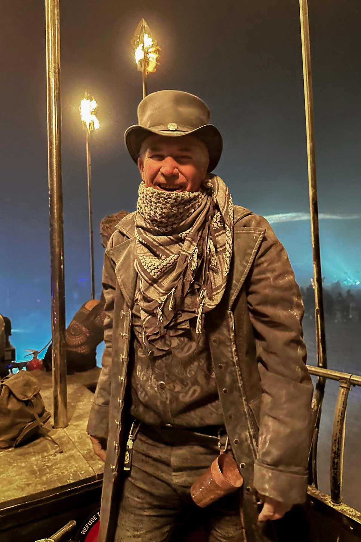 Steampunk man in leather coat with fire torches at night