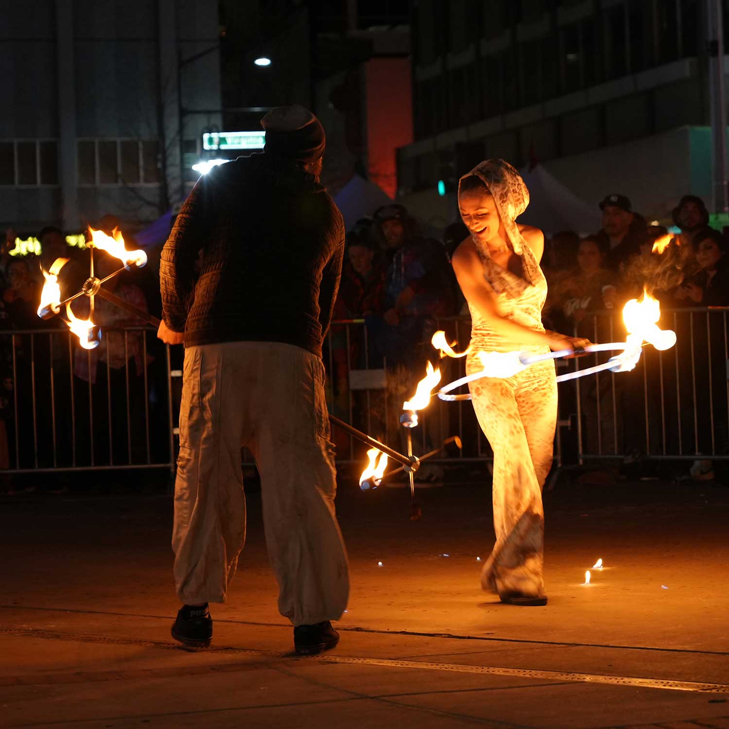 Two fire performers with flaming props at night street event