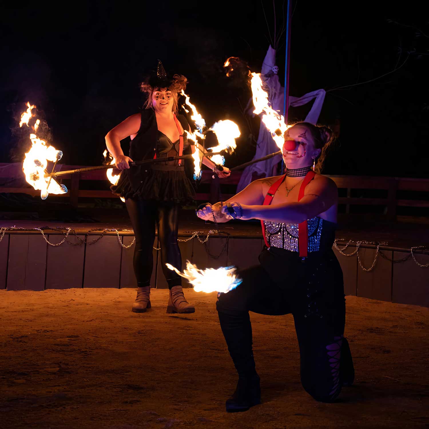 Two costumed performers spinning fire batons at outdoor night event
