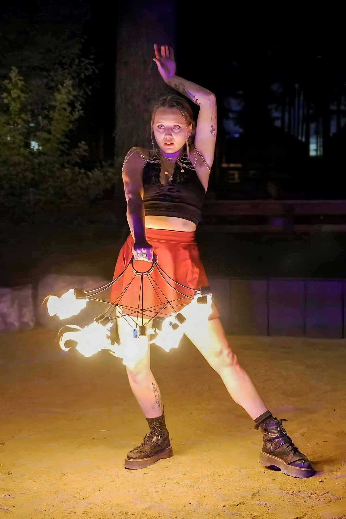 Dancer posing with glowing spider-web fire prop in purple light