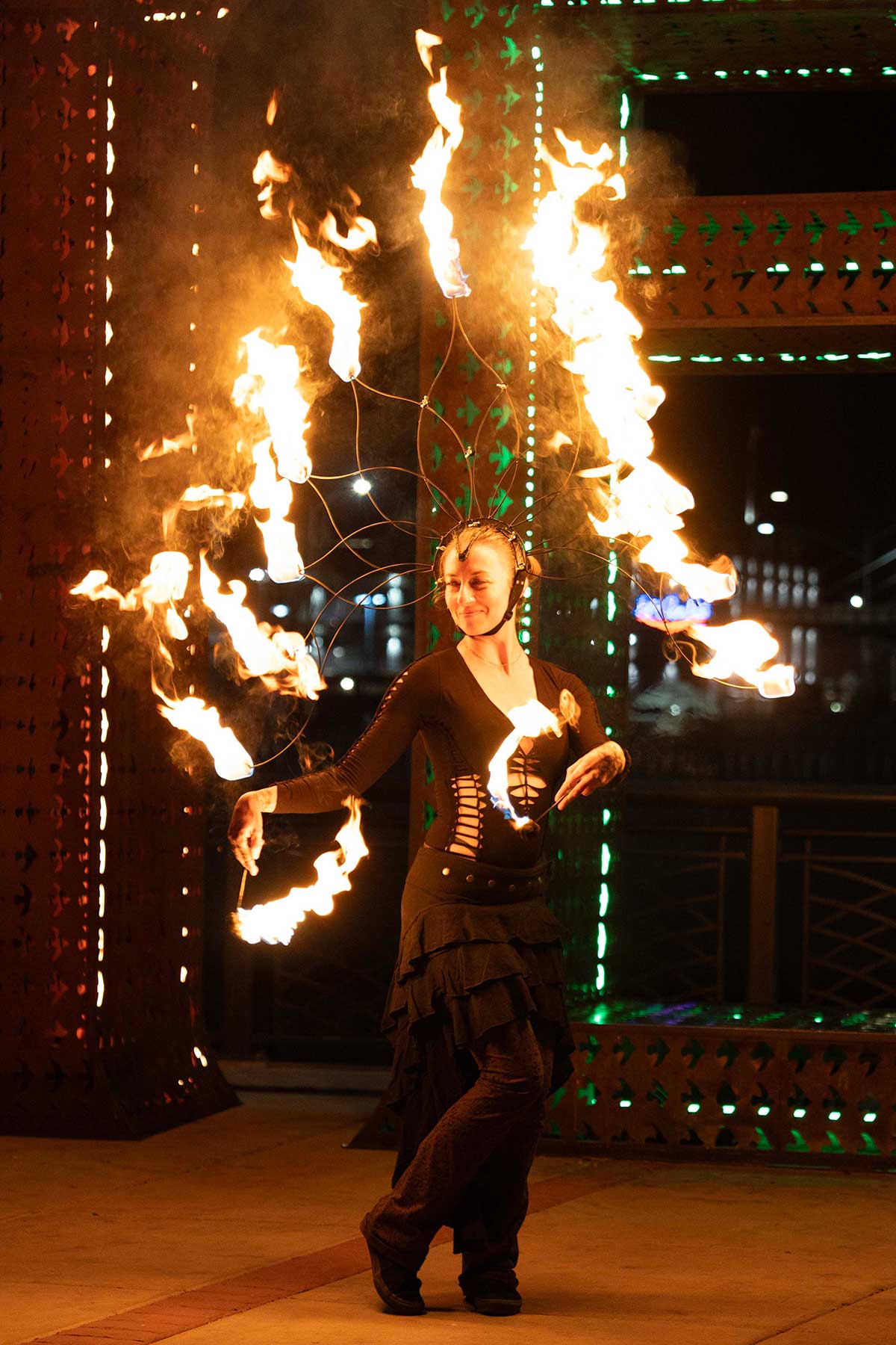 Fire performer with wire headdress spinning poi at urban night festival