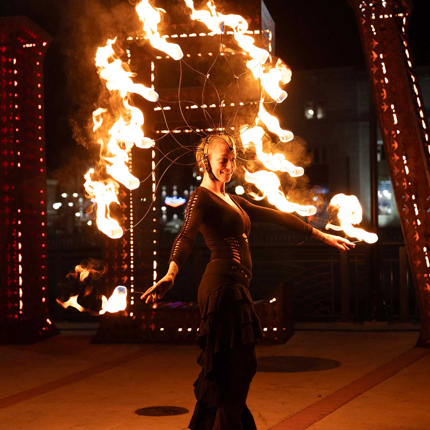 Fire performer with elaborate flaming headdress at urban night festival