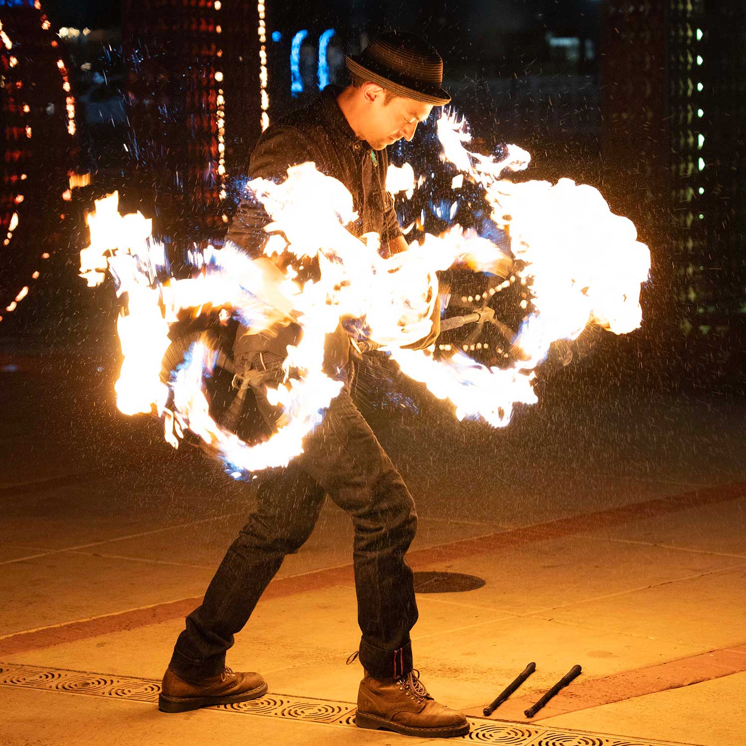 Performer in hat spinning blazing fire fans with sparks flying