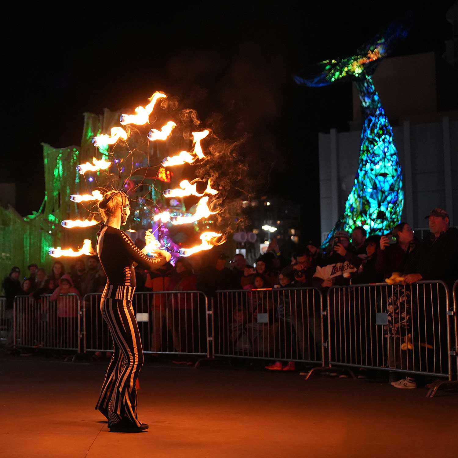 Fire performer spinning multi-wick fans at outdoor night festival