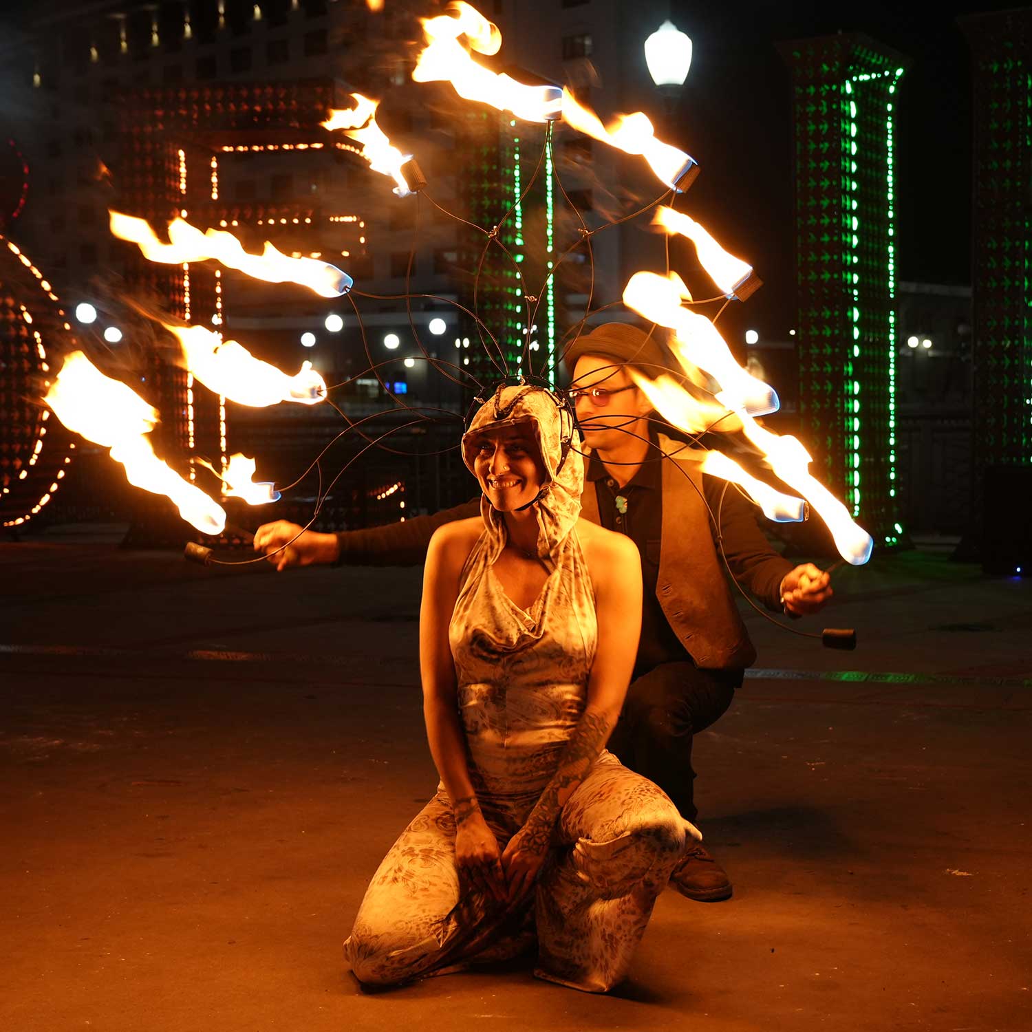 Two performers with elaborate flaming headdresses at urban night festival