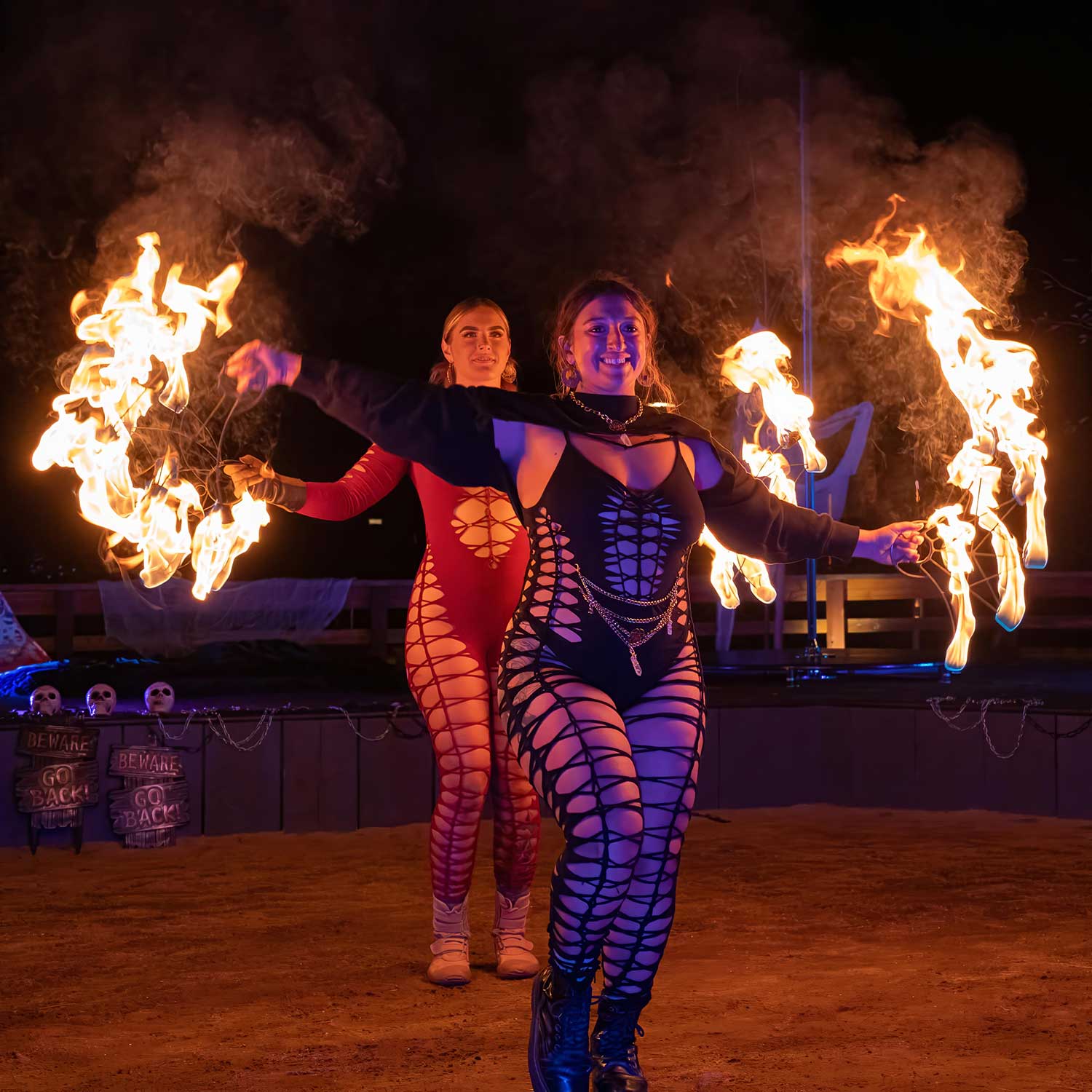 Two costumed fire poi performers walking forward at Halloween event