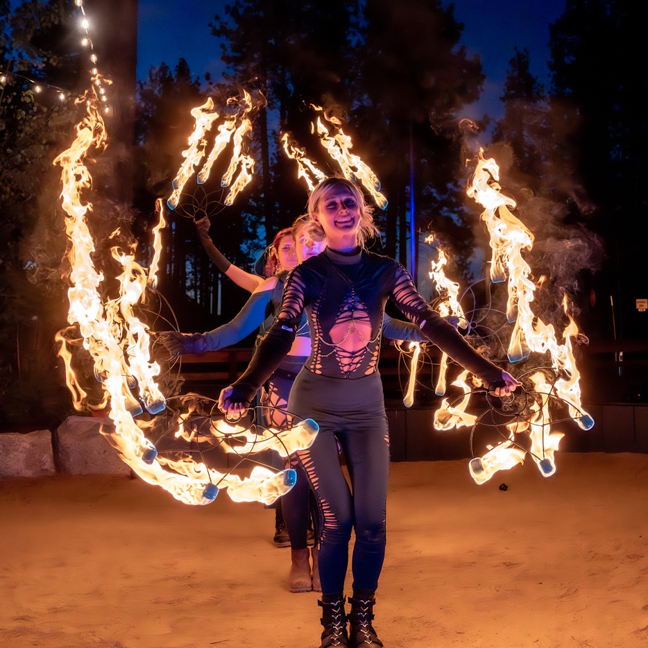 Two performers holding wide fire fans like wings of flame