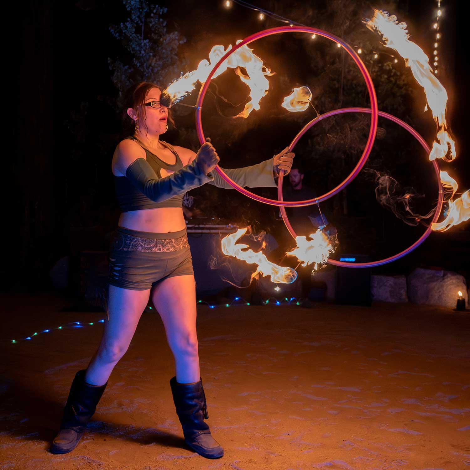 Fire hoop performer spinning two flaming rings at outdoor night event