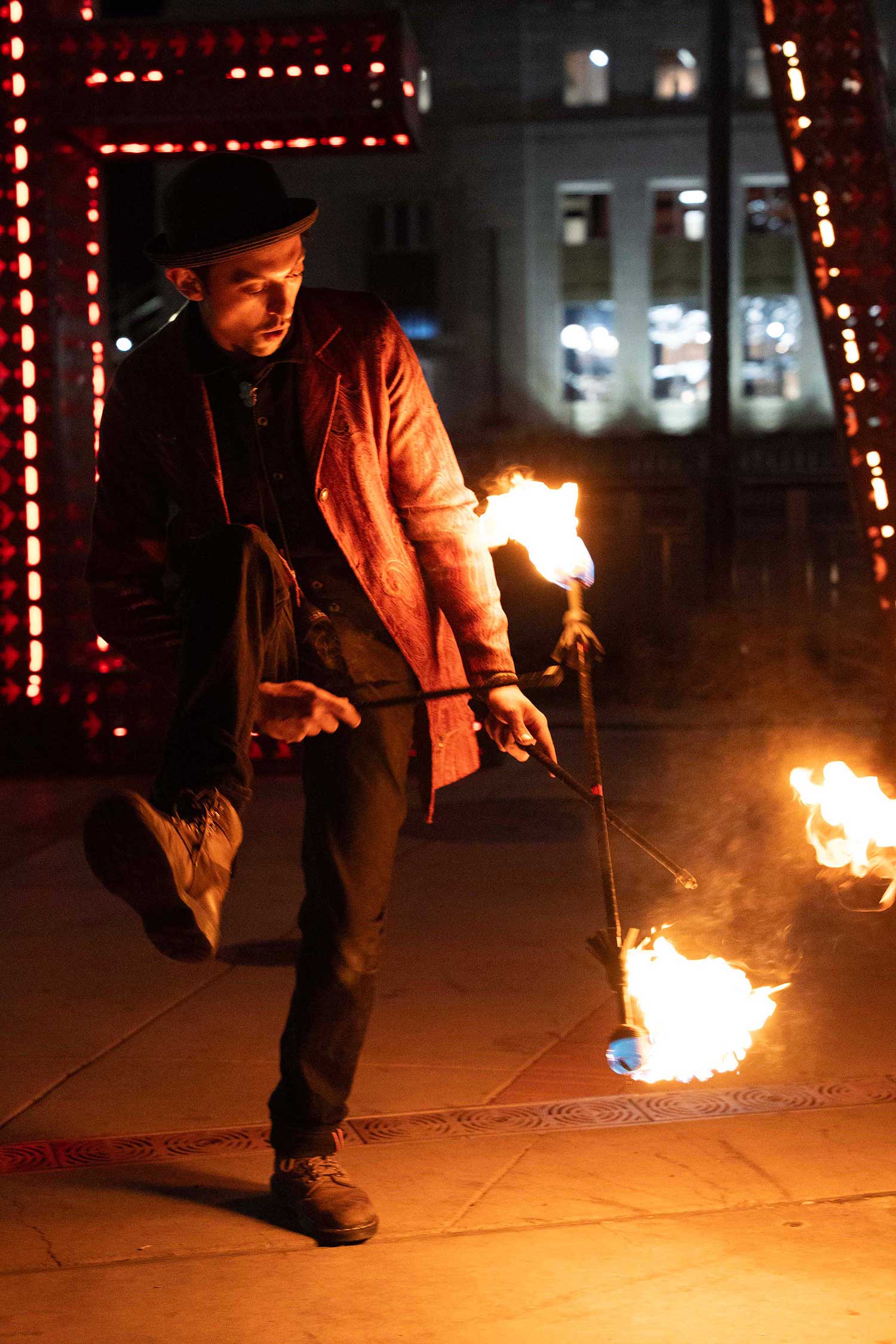 Fire performer in red coat and hat wielding staff