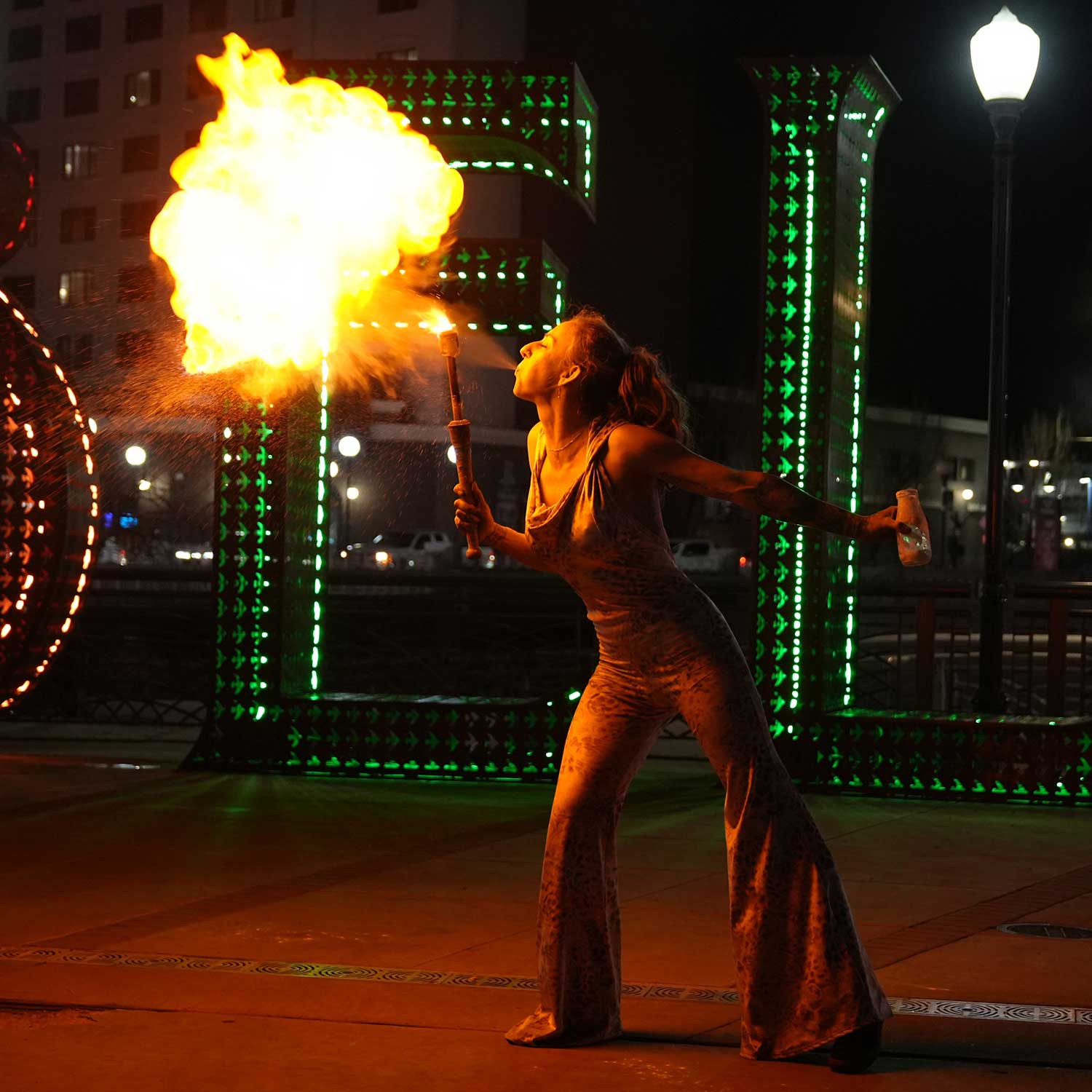 Woman fire breathing huge fireball at outdoor night street performance
