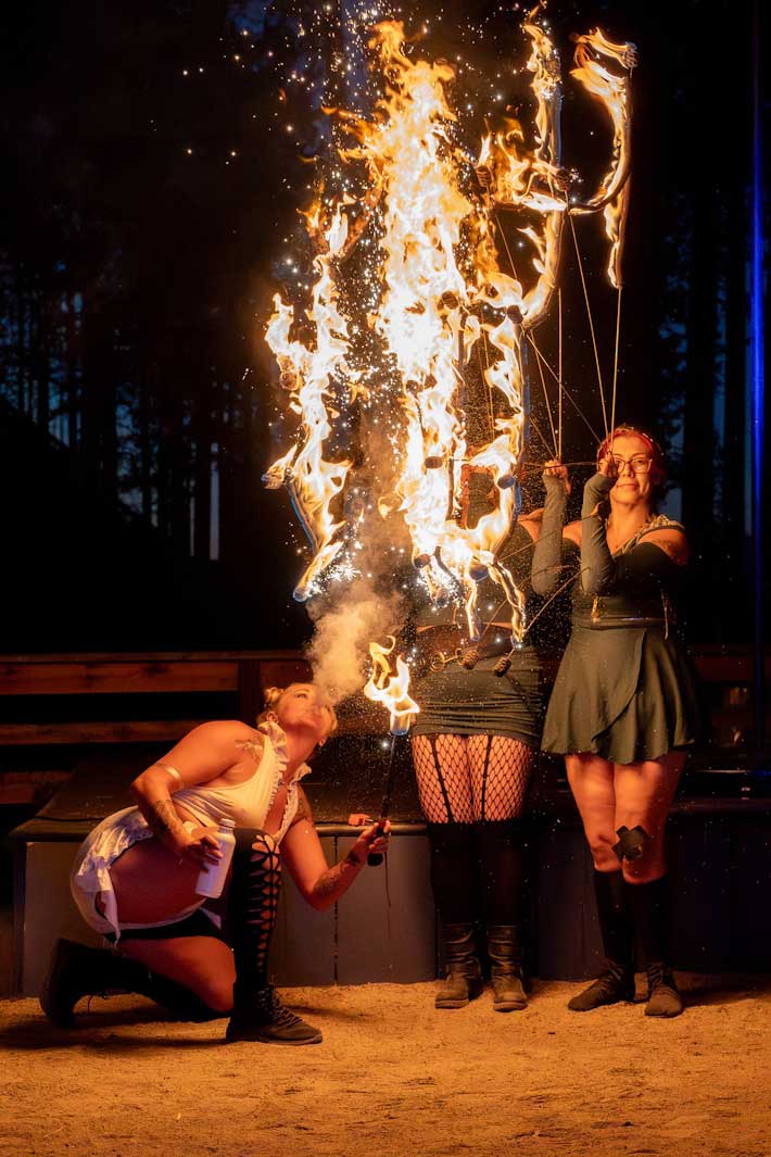 Three fire performers with explosive flames at outdoor night show