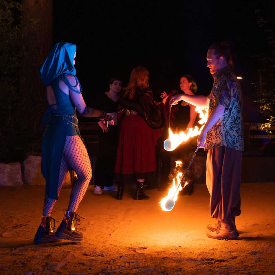 Two fire performers spinning poi in outdoor night setting