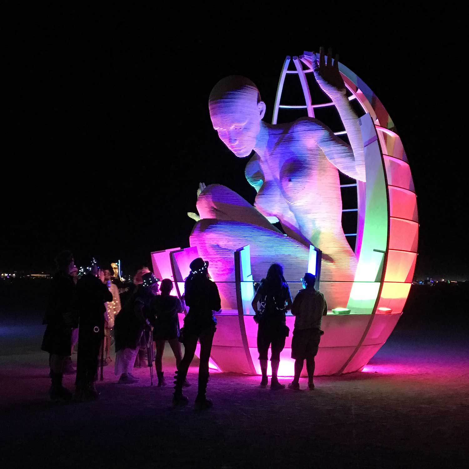 Giant human figure emerging from colorful glowing spherical sculpture