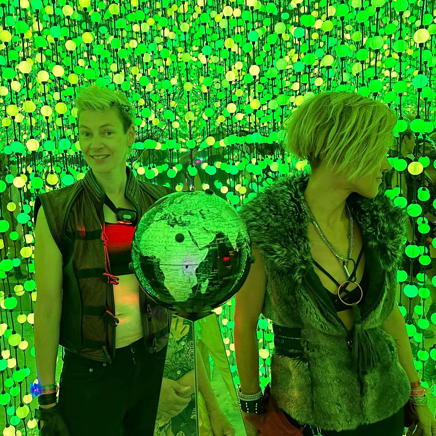 Two festival-goers inside glowing green light orb installation