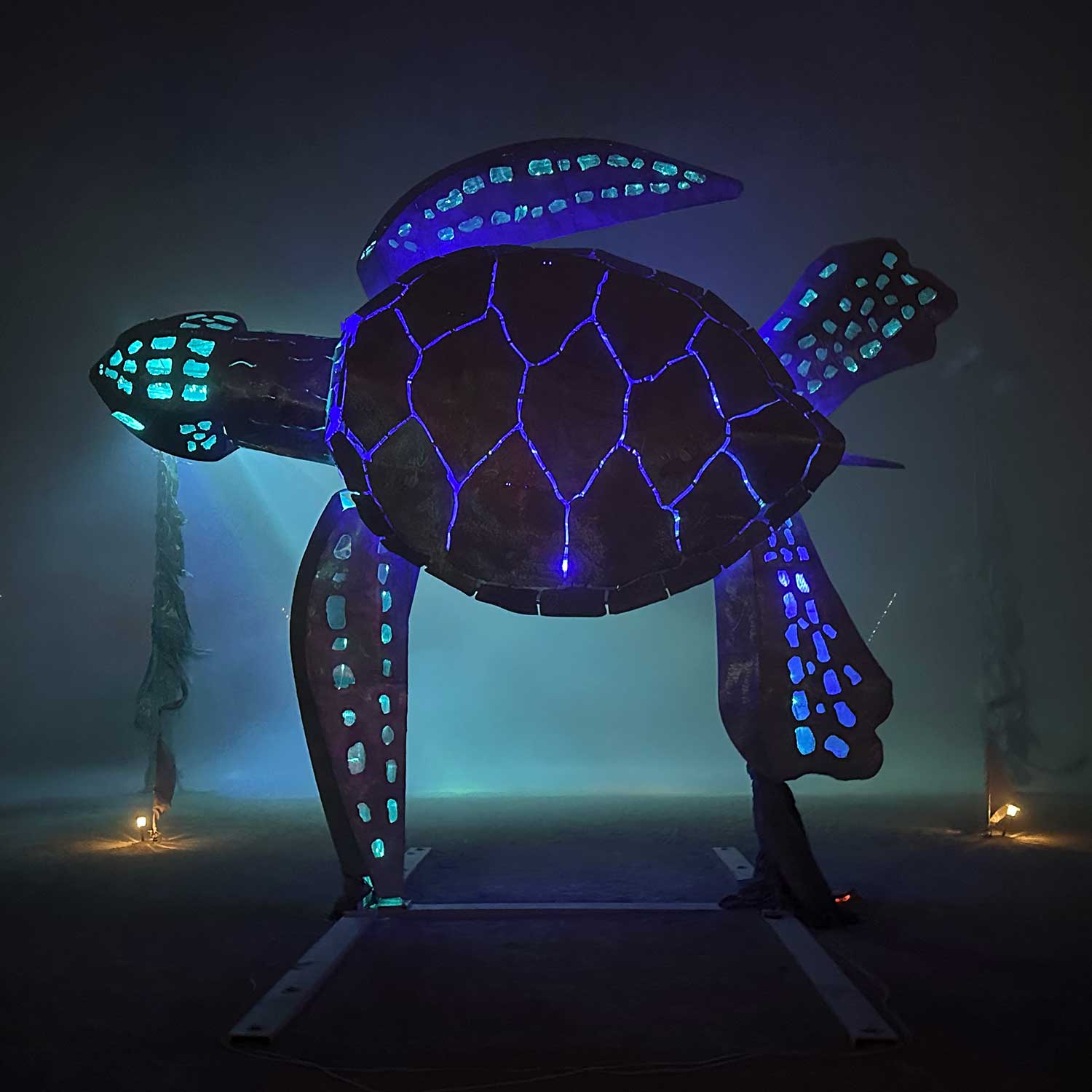 Giant glowing sea turtle sculpture in foggy desert night