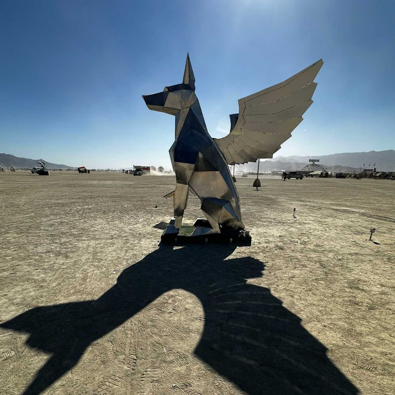 Giant geometric winged dog metal sculpture on desert playa