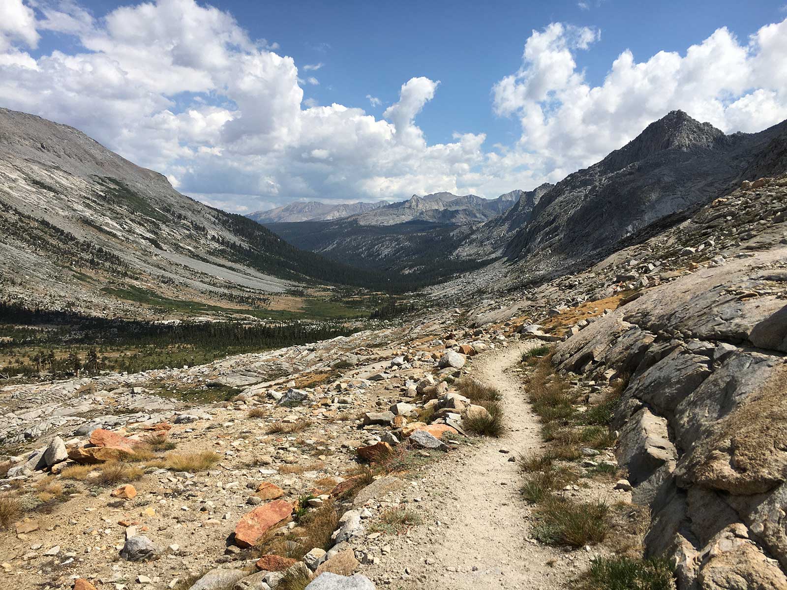 Rocky alpine trail descending through a granite mountain valley