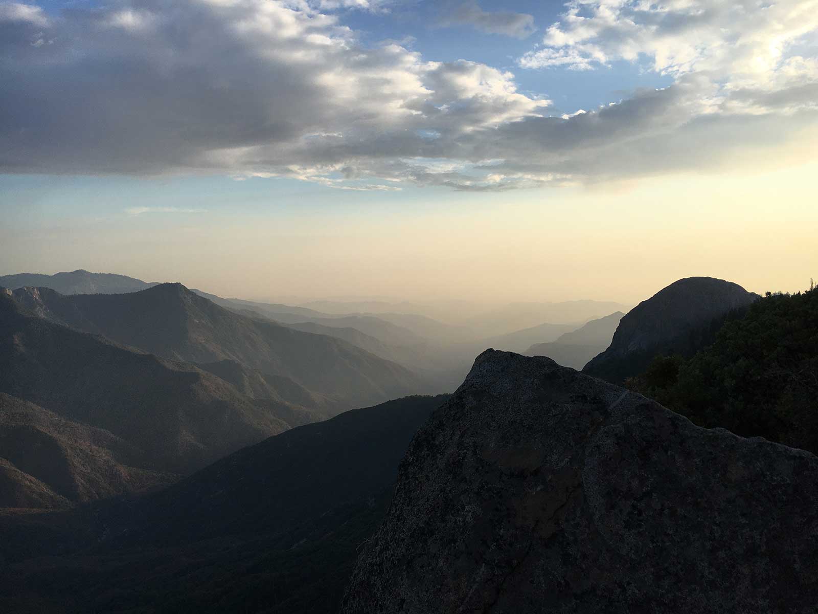 Layered mountain ridges fading into hazy sunset glow